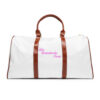 A white duffel bag with brown handles and pink lettering.
