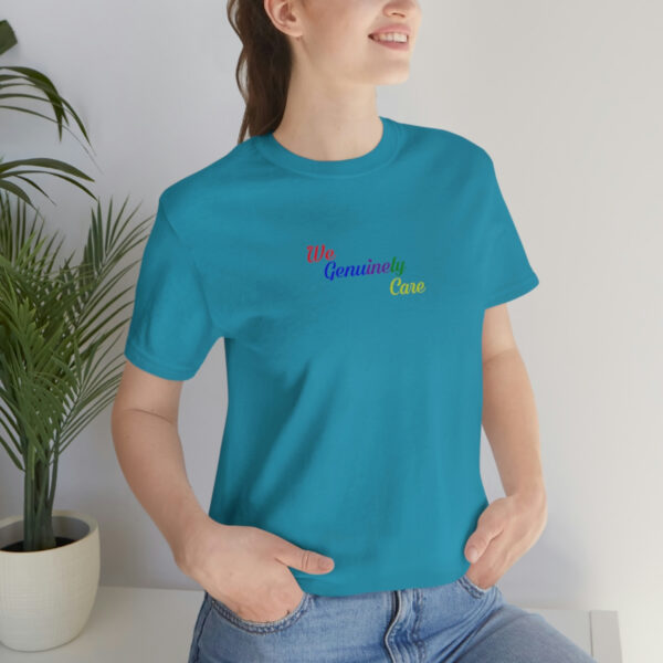 A woman is standing in front of a plant wearing a t-shirt.