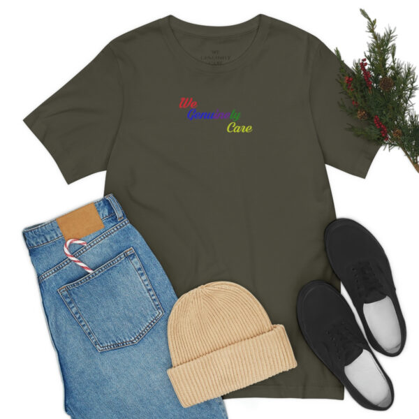 A green shirt with a rainbow on it next to some shoes and a plant