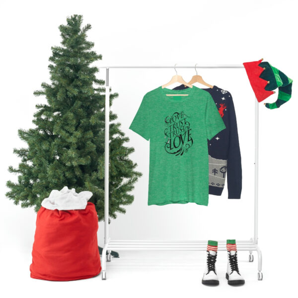 A christmas tree and clothes hanging on a rack.