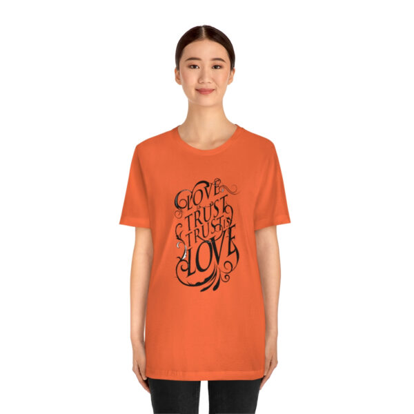 A woman wearing an orange t-shirt with the words " go through love ".