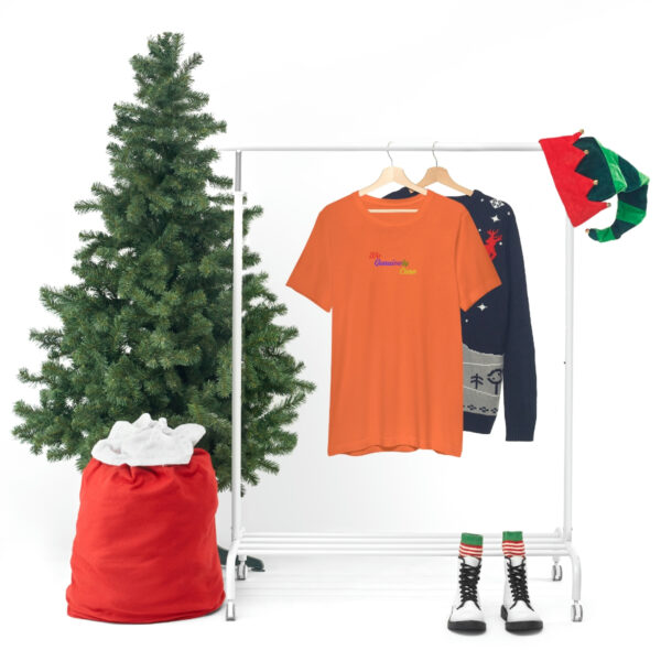 A christmas tree and clothes hanging on a rack.