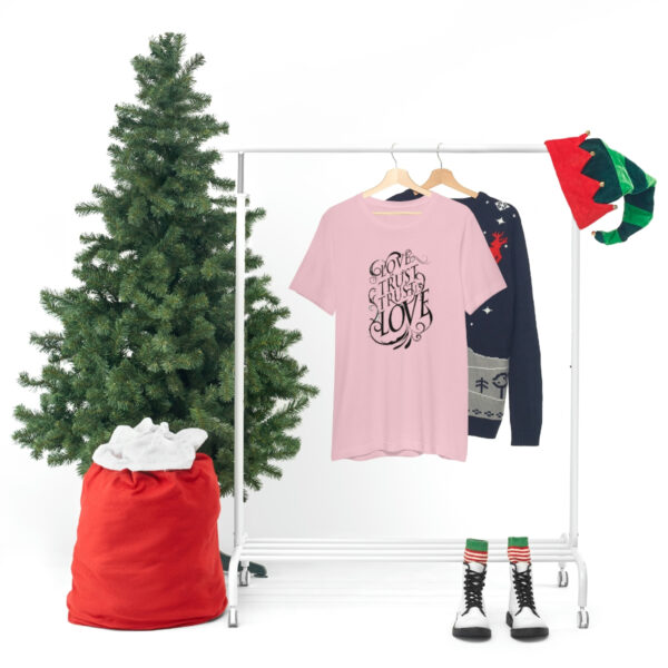 A christmas tree and clothes hanging on a rack.