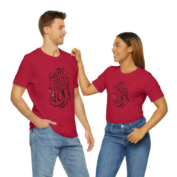 A man and woman holding hands while wearing red shirts.