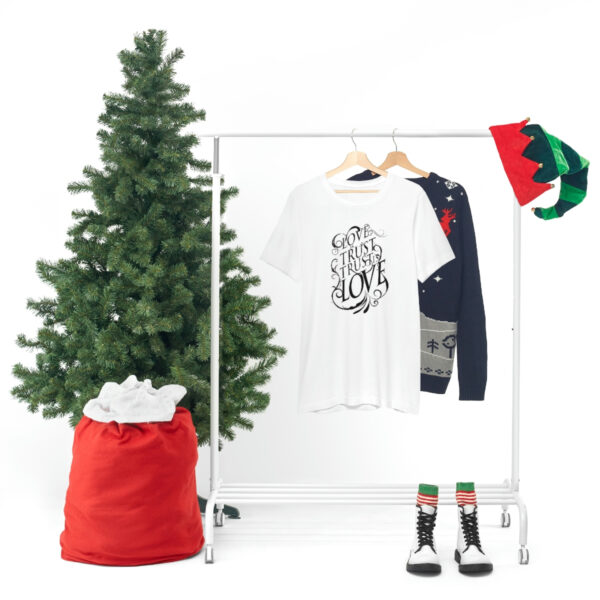 A christmas tree and clothes hanging on a rack.