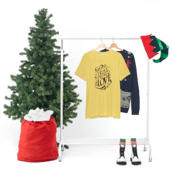 A christmas tree and clothes hanging on a rack.