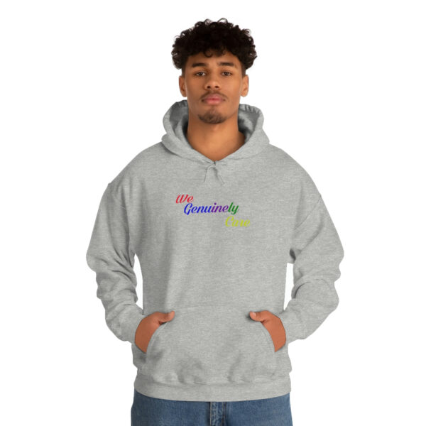 A man in grey hoodie with rainbow lettering.