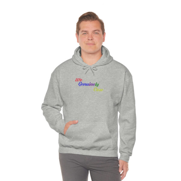 A man in grey hoodie with rainbow lettering.