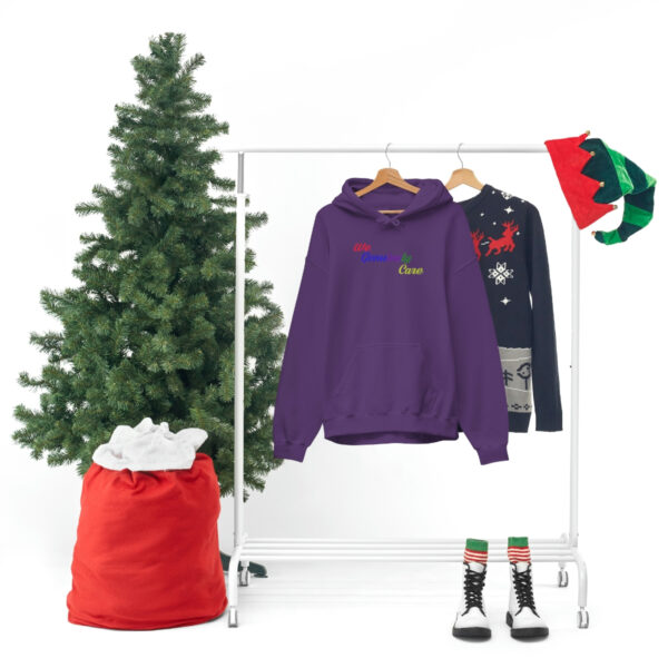 A clothes rack with three different colored sweaters and a christmas tree.