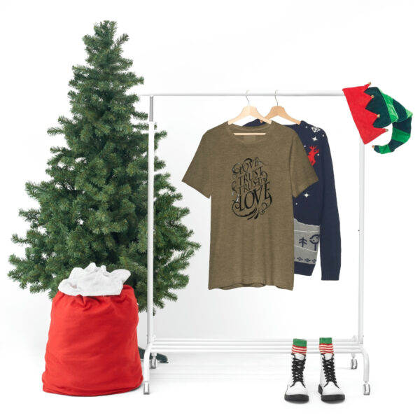 A christmas tree and clothes hanging on a rack.