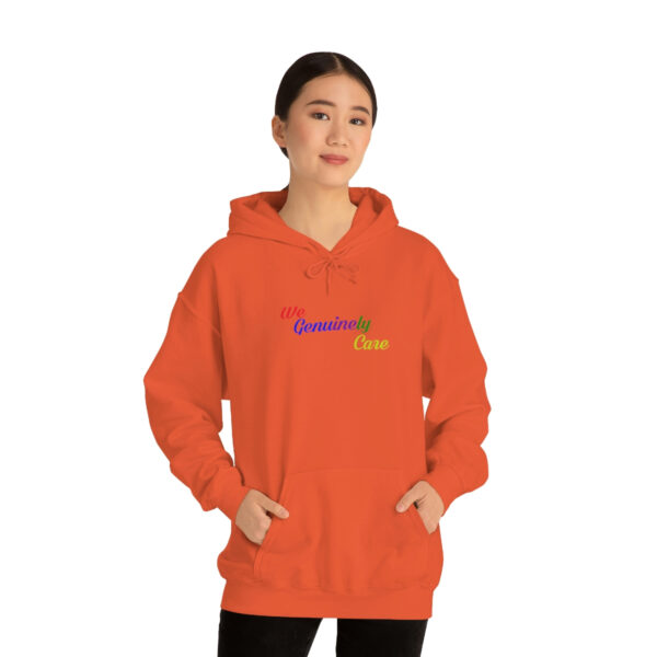 A woman in an orange hoodie with her hands in pockets.