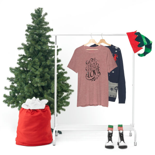 A christmas tree and clothes hanging on a rack.