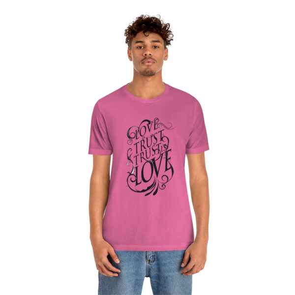 A man wearing a pink t-shirt with the words " love " written on it.