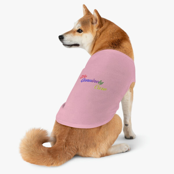 A dog sitting on its back legs wearing a pink shirt.