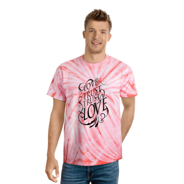 A man wearing a pink tie dye t-shirt with the words " god is great love ".