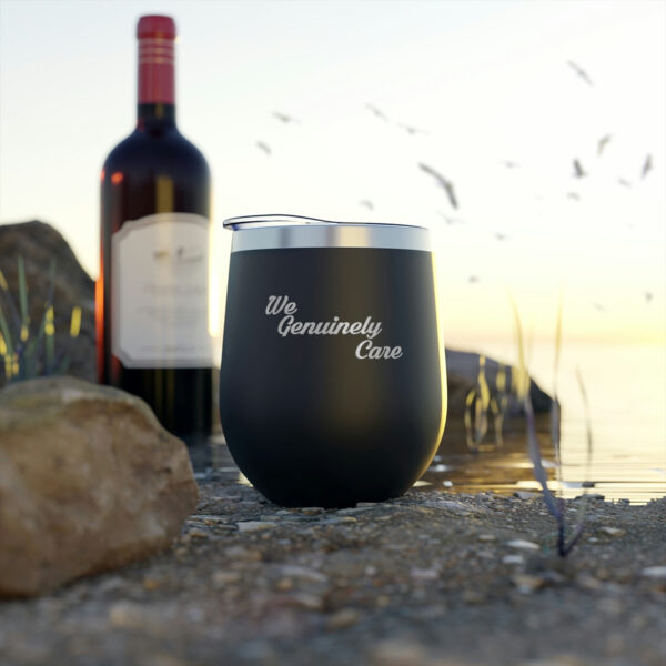 A wine glass sitting on top of the ground next to a bottle.