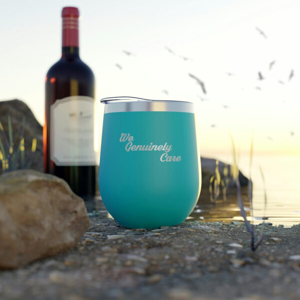 A wine glass sitting on top of the ground next to a bottle.