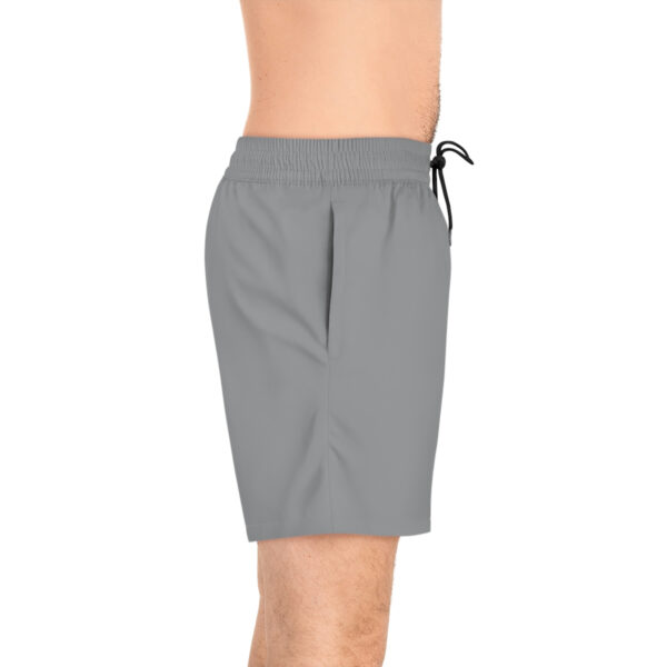 A man wearing grey swim trunks with an elastic waist.