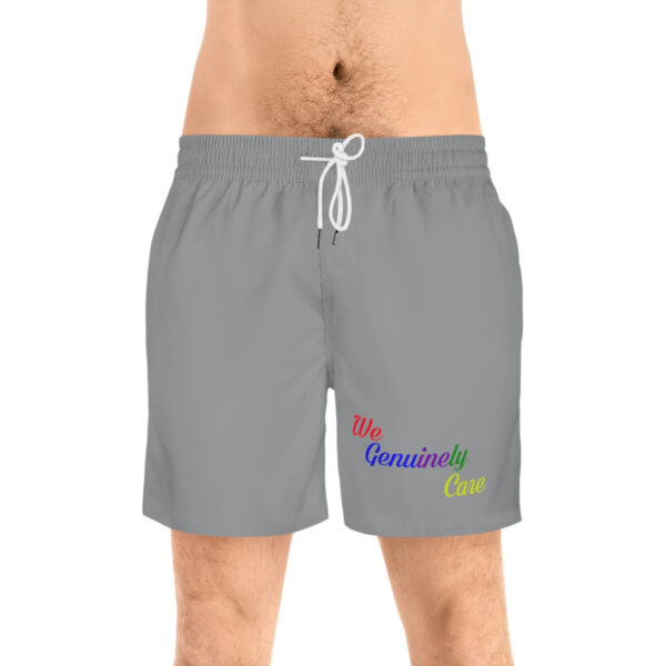 A man wearing grey swim trunks with the words " be beautiful " on it.