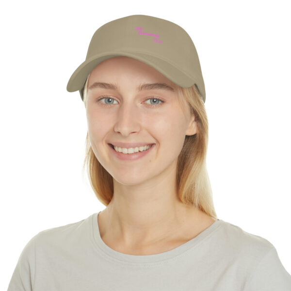 A woman wearing a tan hat with pink lettering.