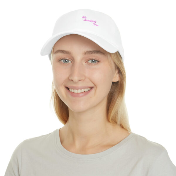 A woman wearing a white hat with pink lettering.